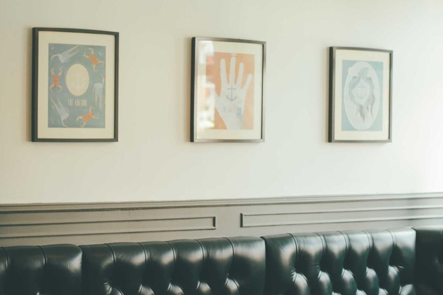 Panelled wainscot beneath framed prints above a tufted leather bench