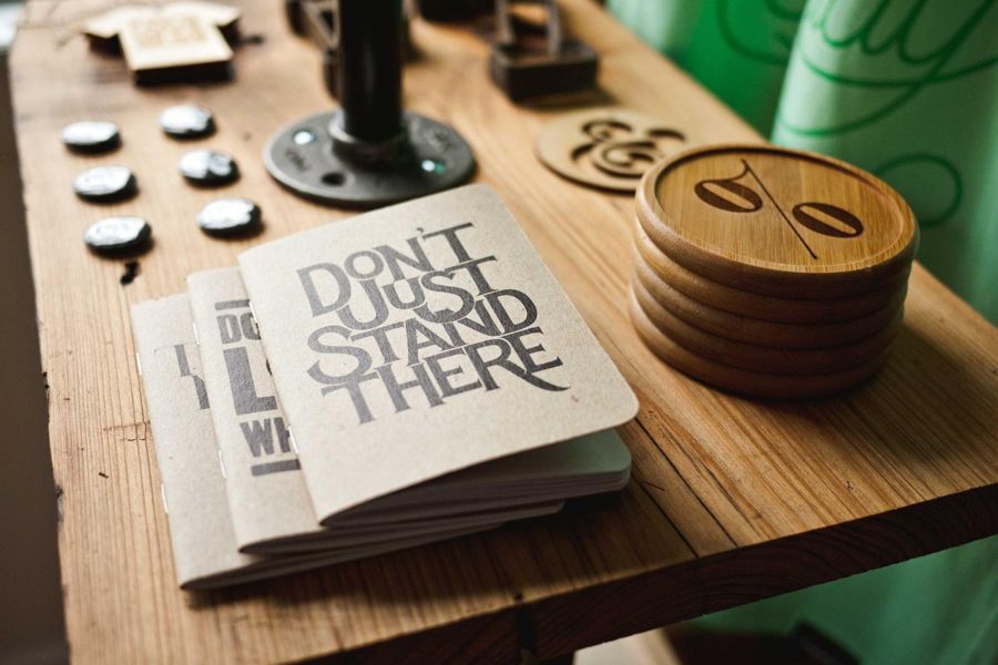 Stack of round wooden coasters and kraft notebooks on a plank shelf